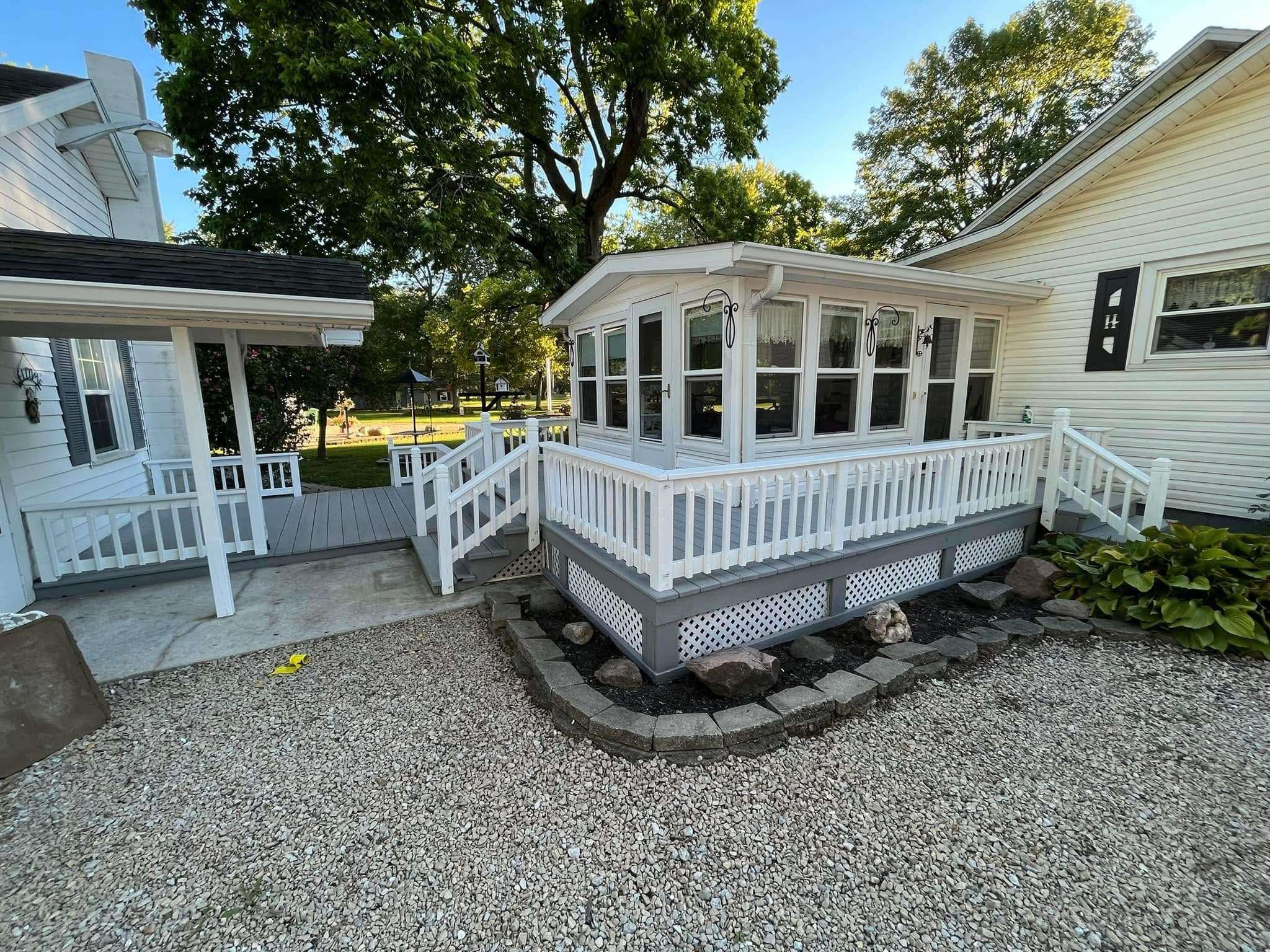 Remodeled sunroom exterior with clean siding and gravel landscaping